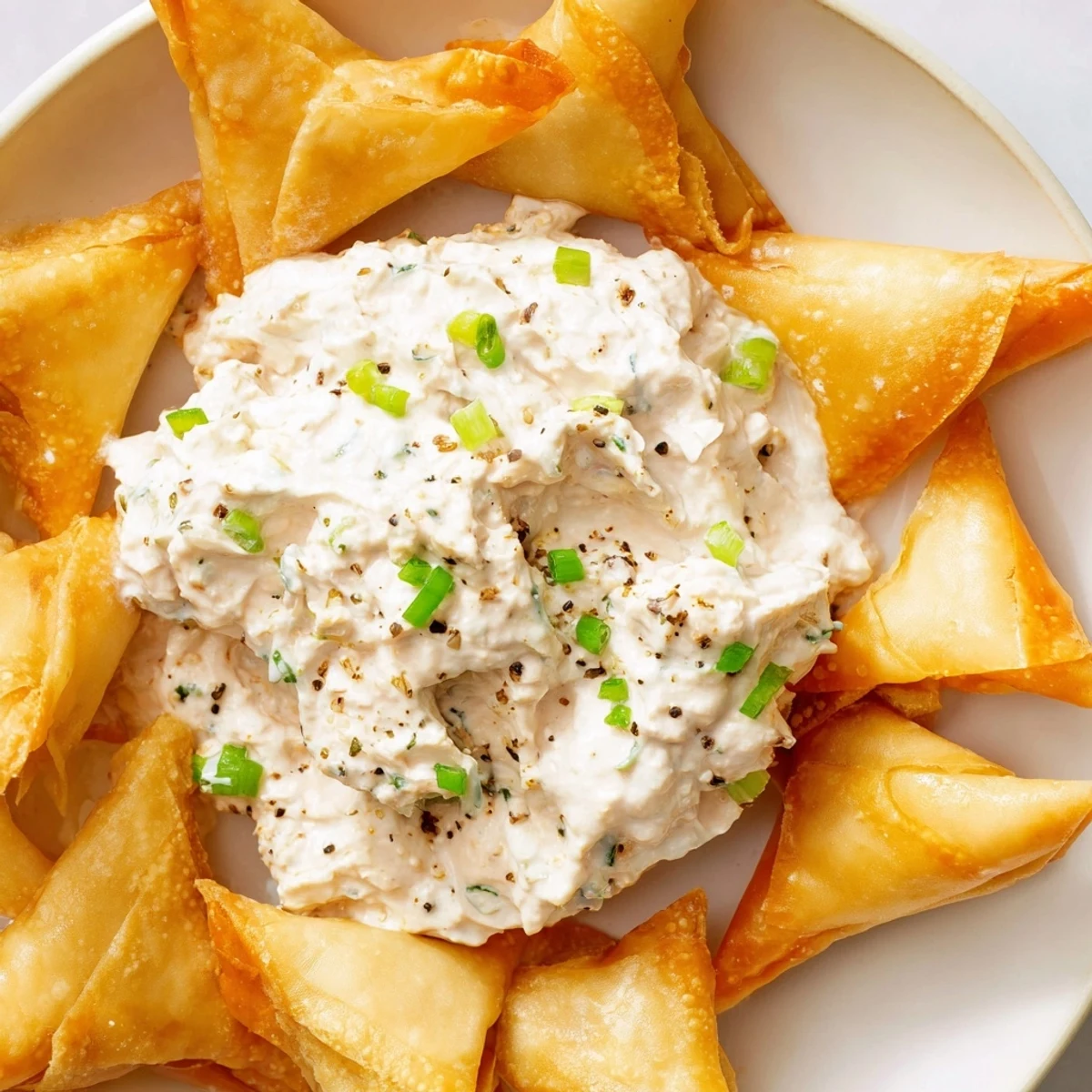 Air Fryer Lumpia Chips with their golden-brown color next to creamy chicken cream cheese dip, ready to eat.