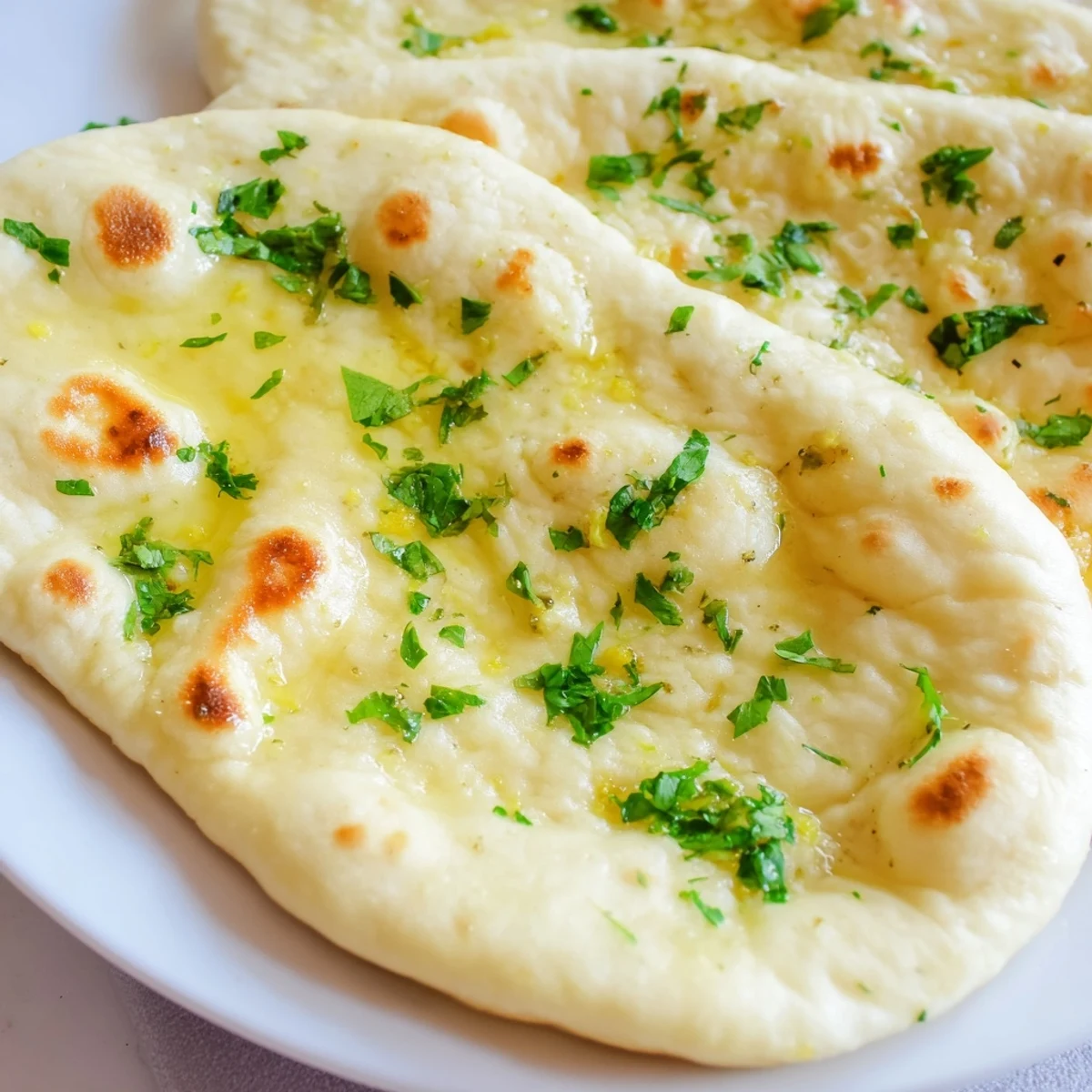 Warm, golden Homemade Garlic Naan Bread, brushed with garlic butter and ready to enjoy with a savory meal.
