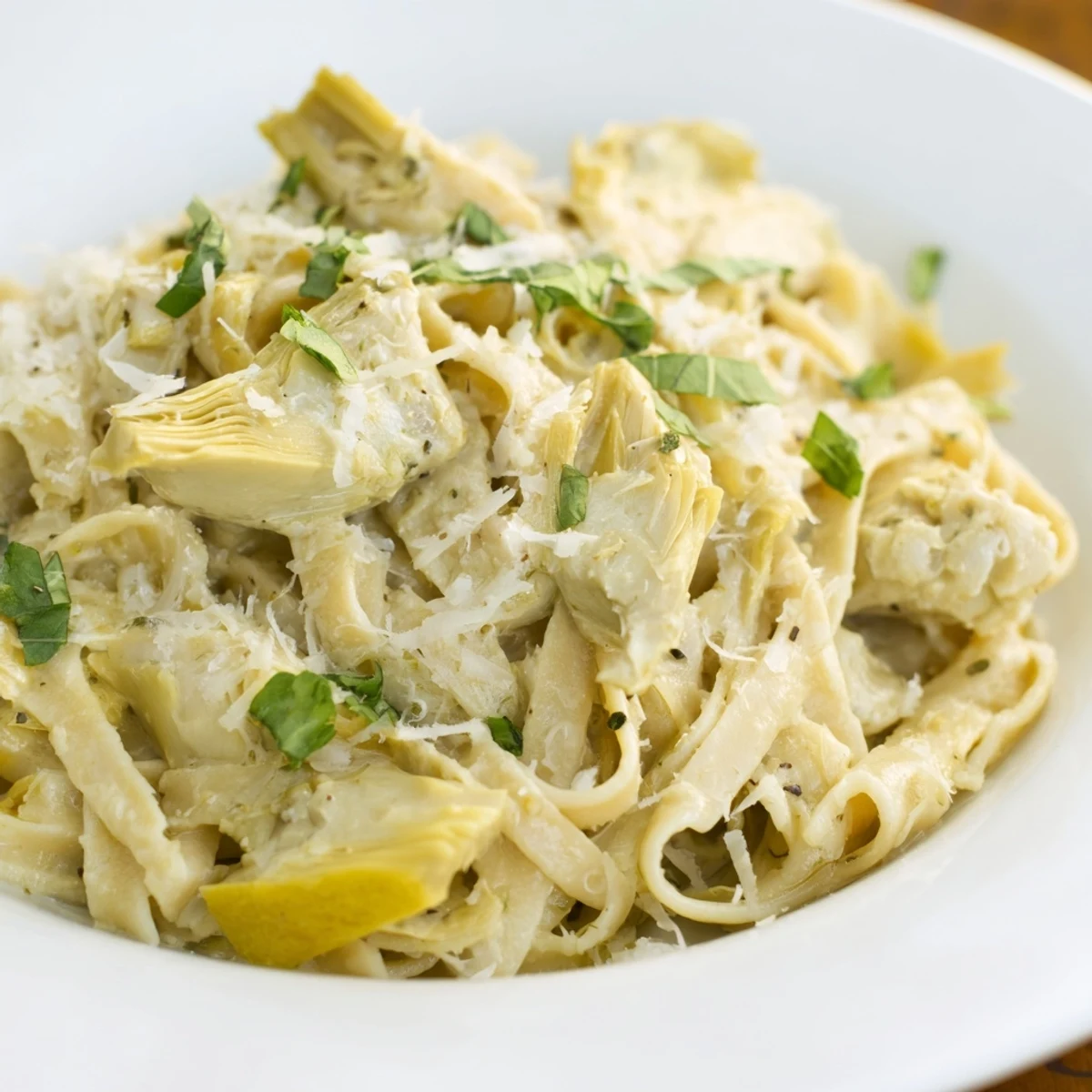 Golden Creamy Lemon Artichoke Pasta, garnished with fresh basil, ready for a delightful dinner.