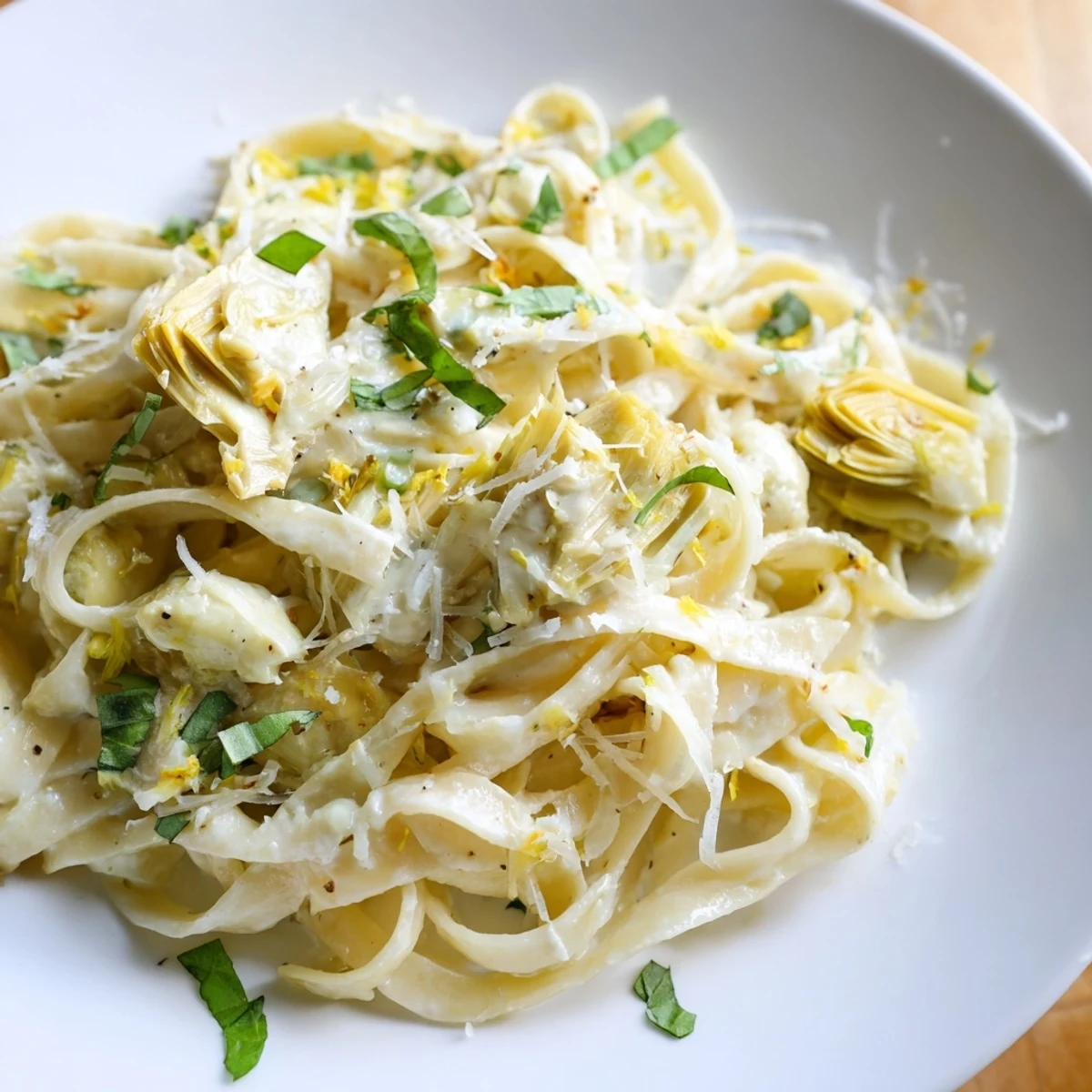 A vibrant creamy sauce coats this Lemon Artichoke Pasta, a vegetarian delight with tender artichokes.