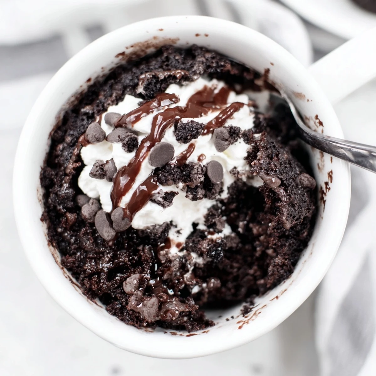 Warm, gooey Oreo mug cake topped with whipped cream, perfect for a quick and easy dessert.