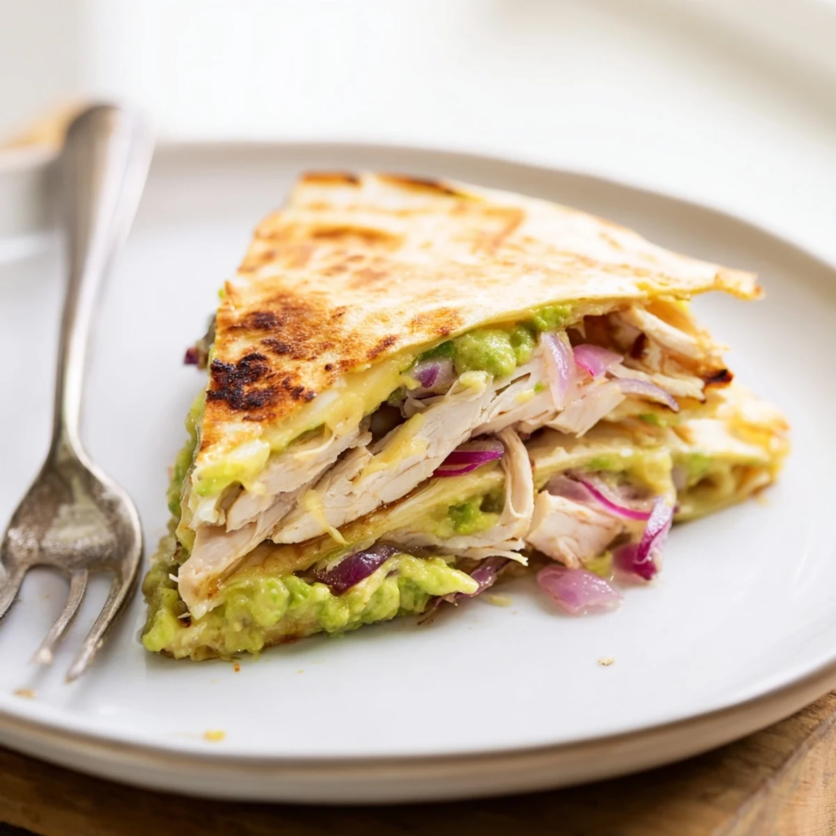 Golden-brown Chicken Avocado Quesadilla wedges with melted cheese and creamy avocado mash.