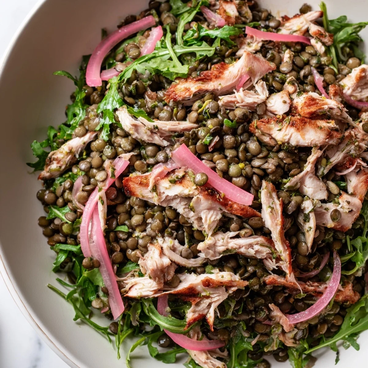 A vibrant Lentil & Chicken Spring Salad with tender lentils, juicy roasted chicken, and peppery arugula topped with tangy pickled onions.  