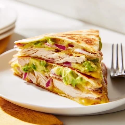 Fresh cilantro and sliced red onion garnish this hearty Chicken Avocado Quesadilla.