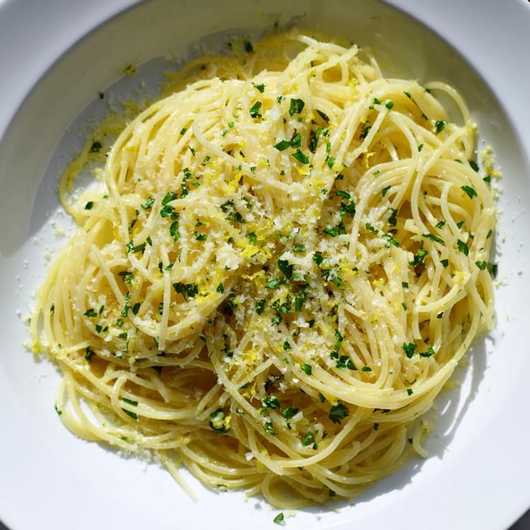 Bright, flavorful photo of Lemon Capellini, ready to eat, with a sprinkle of fresh herbs.