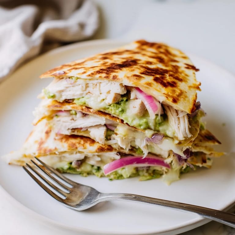 A skillet of hot Chicken Avocado Quesadilla serves with salsa and sour cream.