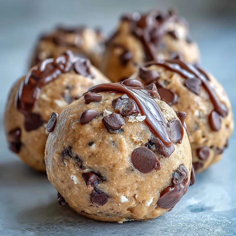 A hand holds a bitten Vegan Chickpea Cookie Dough Bite revealing a creamy interior and chocolate chunks.
