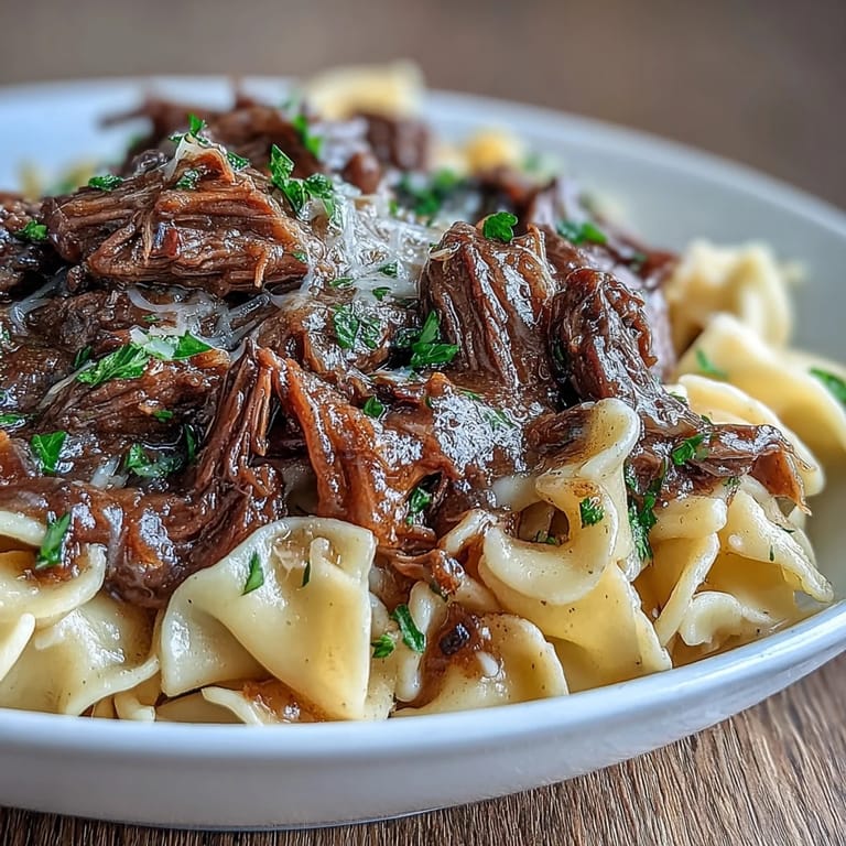 Slow-cooked beef chuck roast simmered with caramelized onions, herbs, and savory broth, served over wide egg noodles.